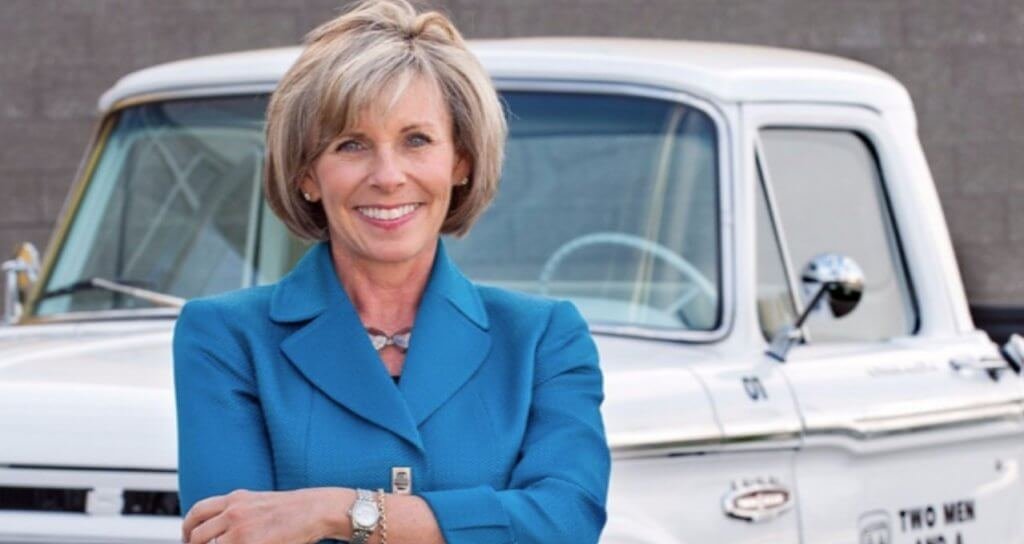 Franchise owner Melanie Bergeron standing in front of the first truck used in two men and a truck history